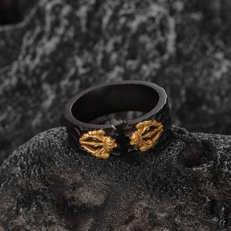 Black ring with gold leaf designs on a dark textured surface