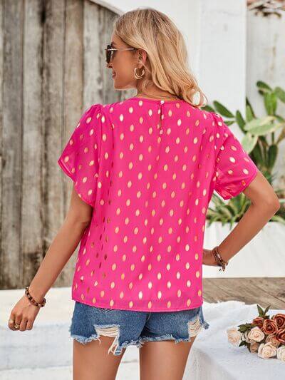 Back view of the Amy Petal Sleeve Top in bright pink with gold accents, styled with denim shorts.