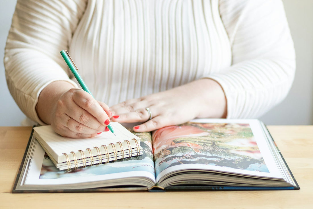 A woman writing thoughtfully with a pen in a notebook