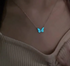 Necklace with a blue butterfly pendant on a beige top