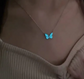 Necklace with a blue butterfly pendant on a beige top