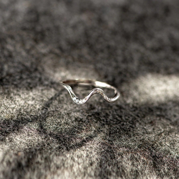 Silver wave-shaped ring on a textured stone surface