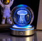Glass orb with jellyfish design on a rotating base, illuminated by blue light, with an astronaut figure in the background.