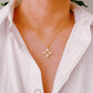 Gold necklace with a cross pendant worn by a person in a white shirt.