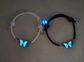 Two bracelets with butterfly charms glowing blue on a neutral background