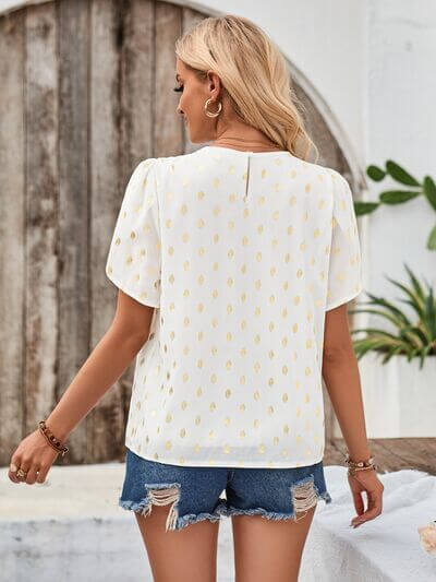 Back view of a woman wearing the Amy Petal Sleeve Top with petal sleeves and gold brush strokes paired with denim shorts.