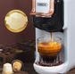 Hibrew coffee machine pouring coffee into a glass cup with capsules and a box in the background.
