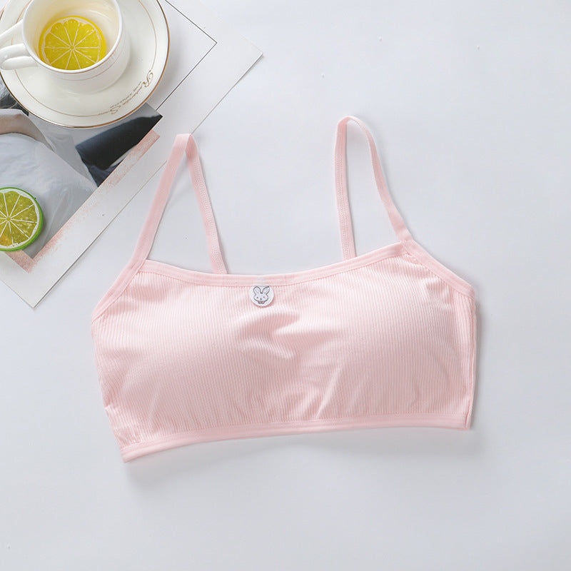 Pink bralette on a light gray surface with a cup of tea and lemon slices in the background.