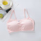 Pink bralette on a light gray surface with a cup of tea and lemon slices in the background.