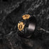 Black ring with gold designs on a textured dark background