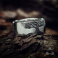 Silver tree ring on a wooden surface with a blurred background
