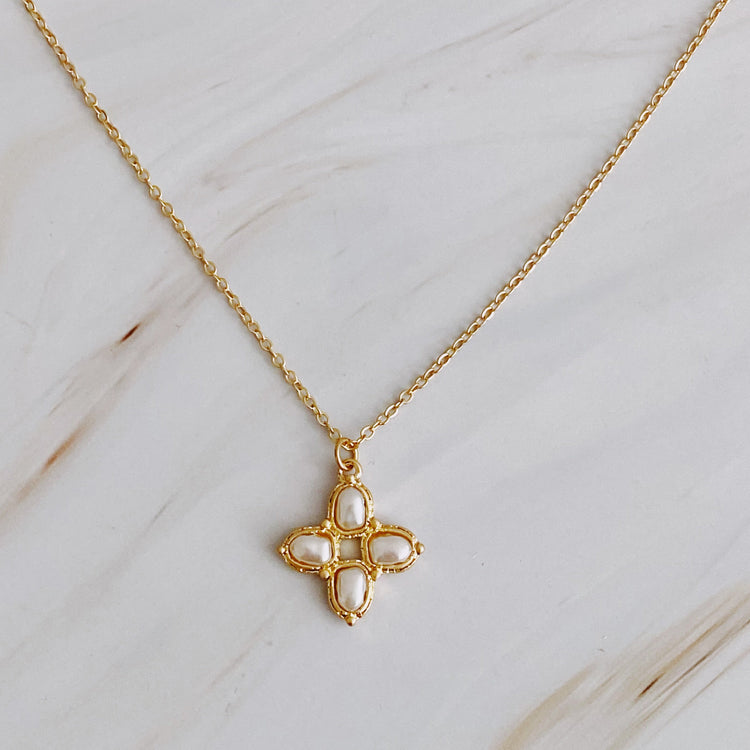 Gold necklace with a cross pendant on a light wooden surface