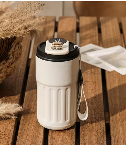 White travel mug with black lid on a wooden surface