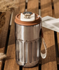 Stainless steel tumbler with brown lid on a wooden surface