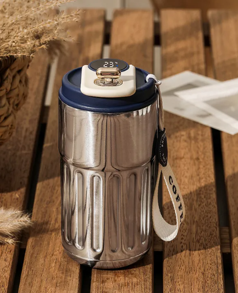 Stainless steel tumbler with a blue lid on a wooden surface