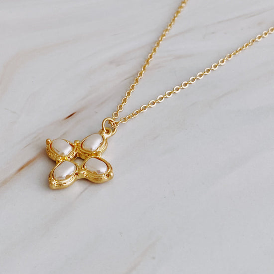 Gold necklace with a butterfly-shaped pendant on a marble surface