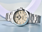 Silver watch with beige dial on a light blue background