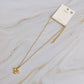 Gold necklace with a pendant on a marble surface, featuring the brand &