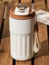 White travel mug with brown lid on a wooden surface