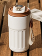 White travel mug with brown lid on a wooden surface