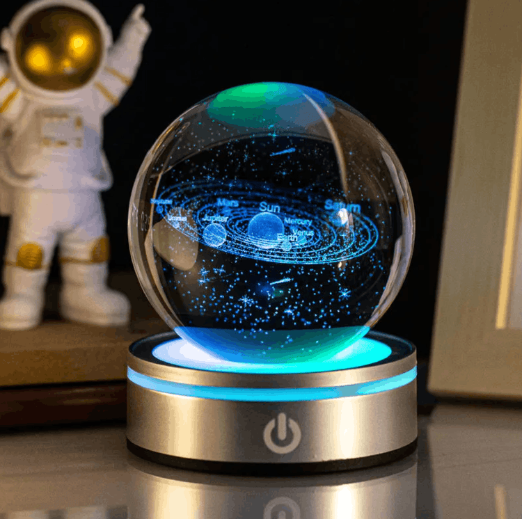 Glass ball with solar system model on a glowing base, with an astronaut figure in the background.