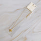 Gold necklace with a clover pendant on a marble surface